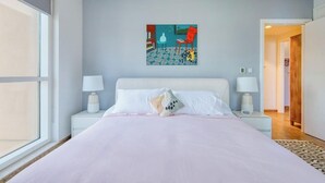 Una camera da letto con un letto grande, due comodini con lampade, un dipinto a parete e vista sull'esterno.