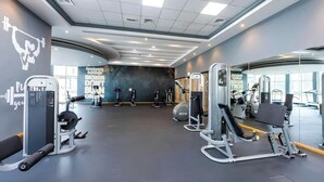 Una palestra con diverse macchine per esercizi, uno specchio a parete e decorazioni motivazionali.