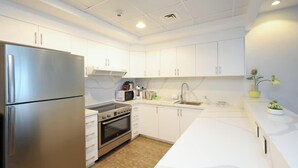 A modern kitchen with white cabinets, stainless steel appliances, and a marble backsplash.