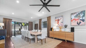 Un espace repas comprenant une table et des chaises, un ventilateur de plafond et des œuvres d’art accrochées aux murs.