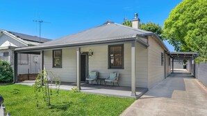 Une maison de plain-pied avec un porche abrité, un petit jardin et un ciel dégagé.
