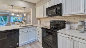 Una cocina moderna con muebles blancos, una estufa negra y un microondas integrado.