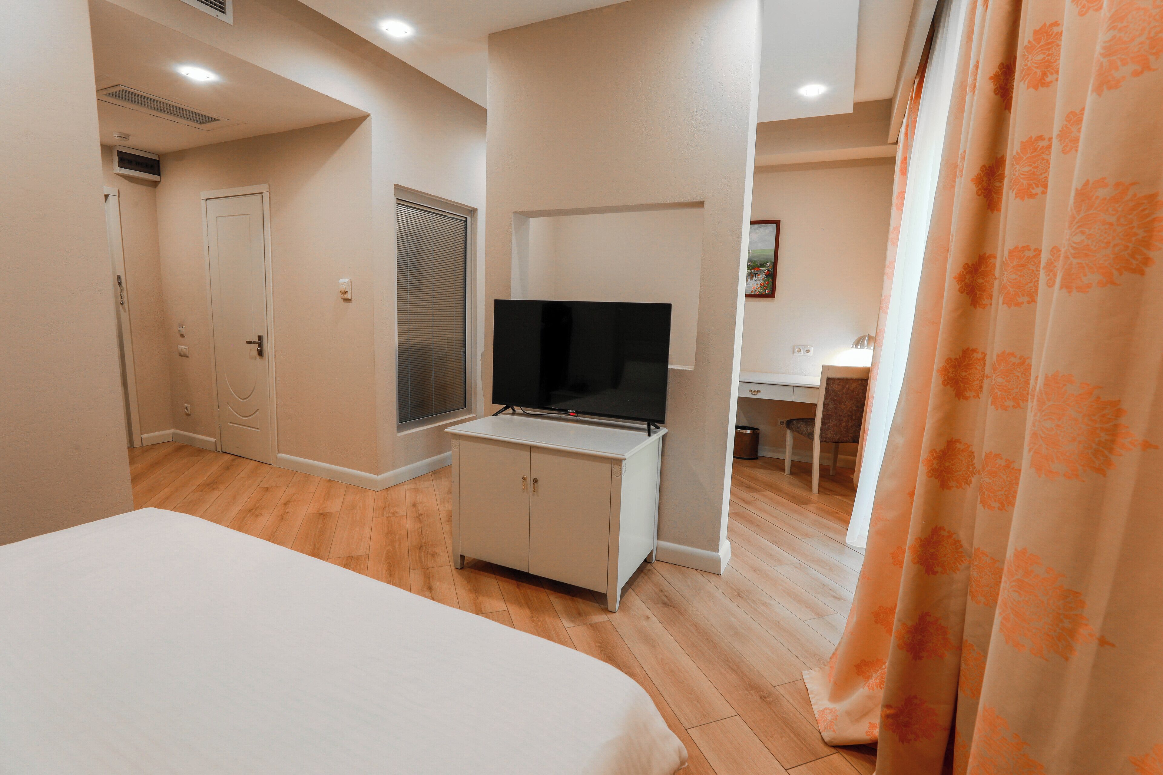 A hotel room with a bed, a TV on a cabinet, a desk, and a chair.