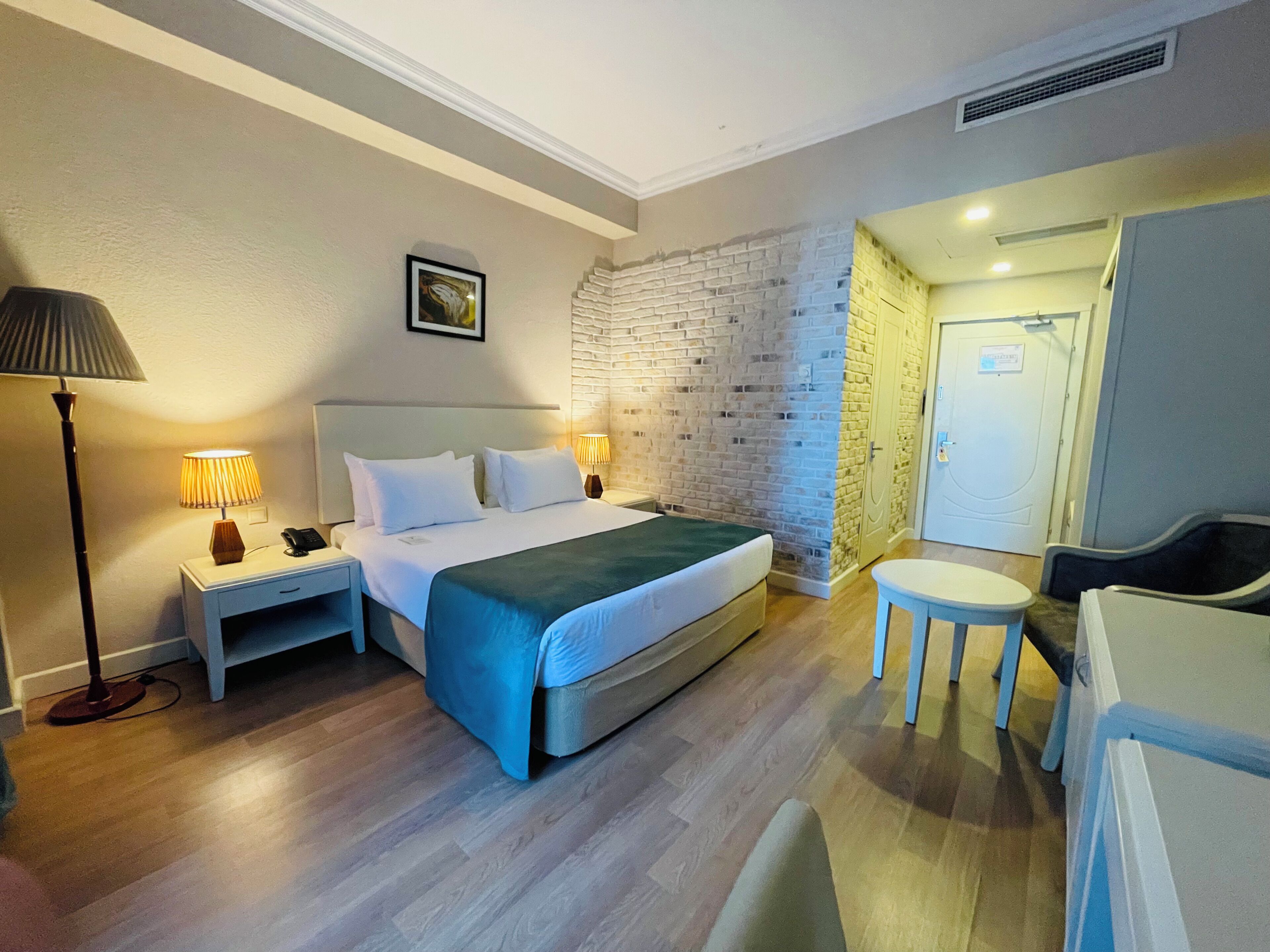 A hotel room with a bed, bedside lamps, a desk, and a chair.