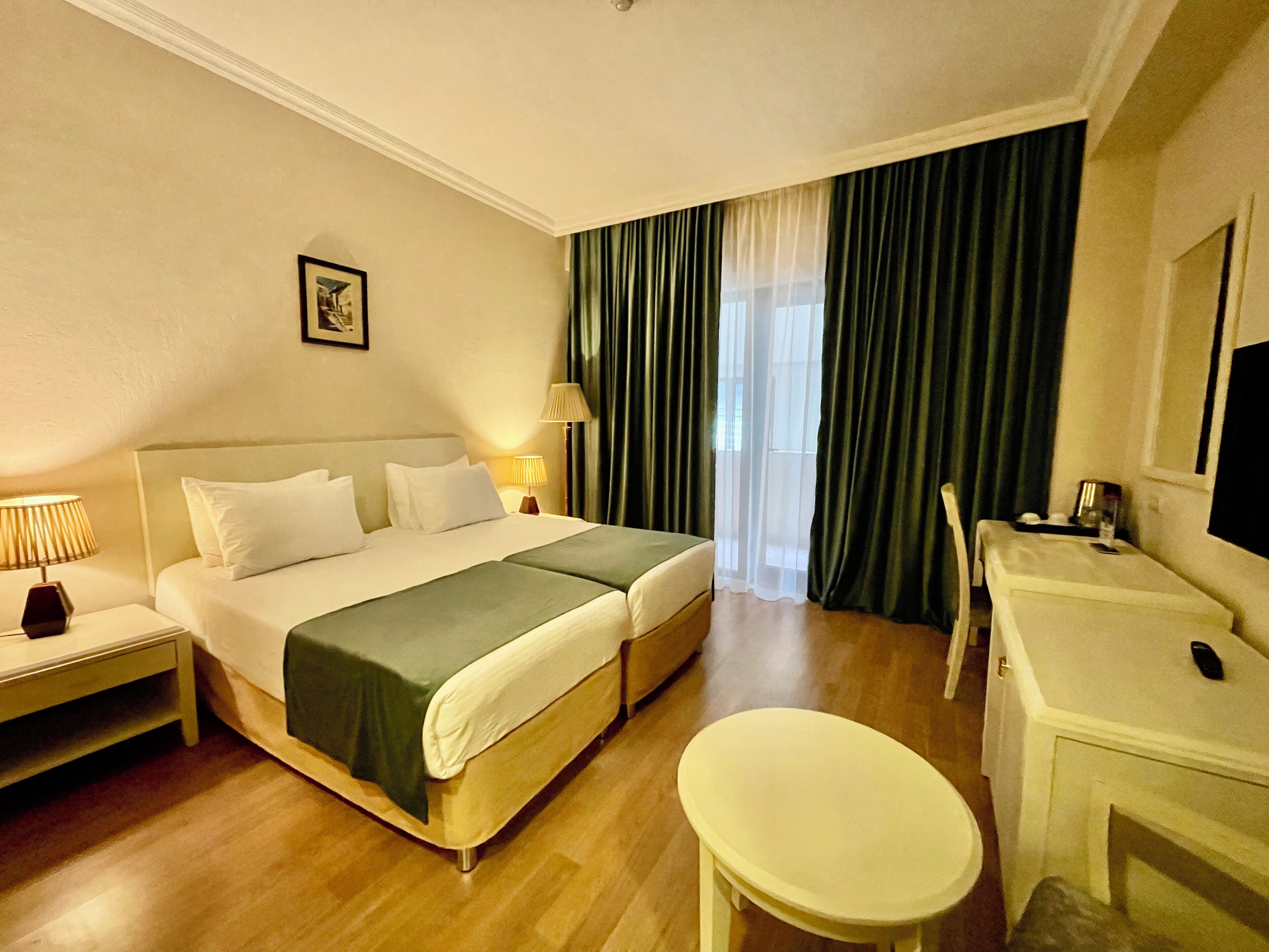 Een hotelkamer met een bed, nachtkastjes, een bureau en een stoel.