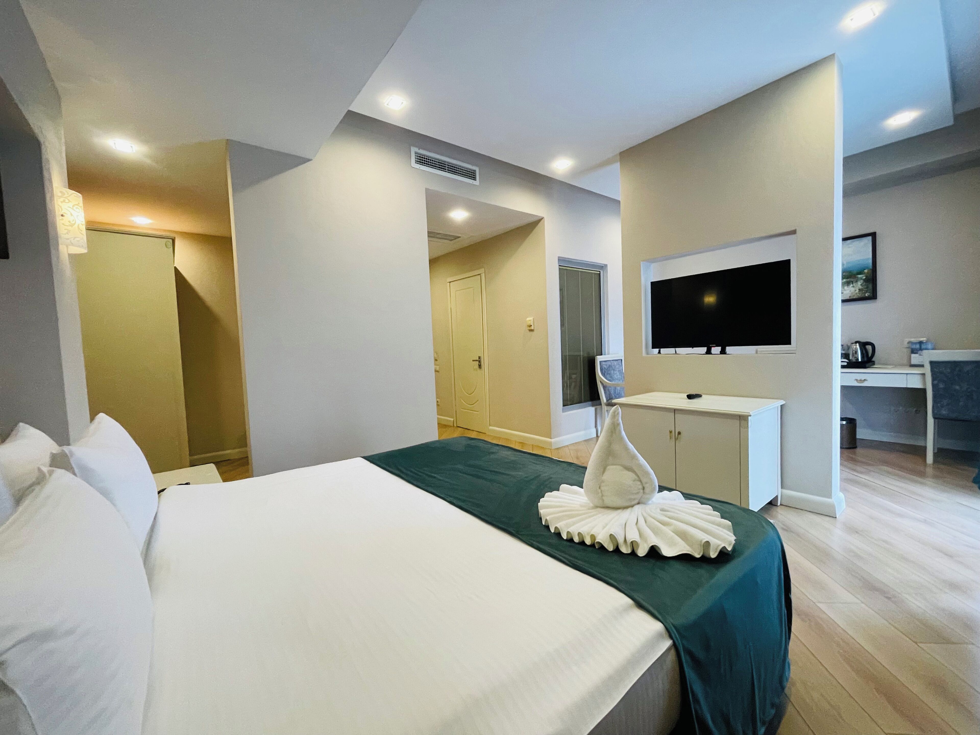 Habitación de hotel con cama, escritorio, televisión y puerta al baño.