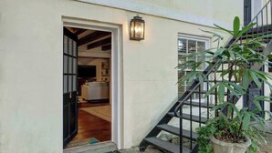 A house entrance with a wooden door, a staircase, and a potted plant. - The Quaint Quarters on Jones, Historic | Quiet (Savannah)