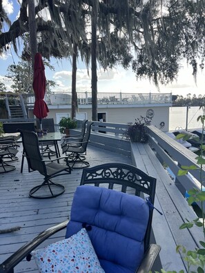 Una terraza con mobiliario exterior, un paraguas rojo y vista al agua.
