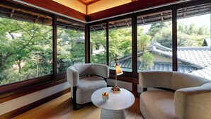 A modern room with large windows, two armchairs, a small table, and a lamp.