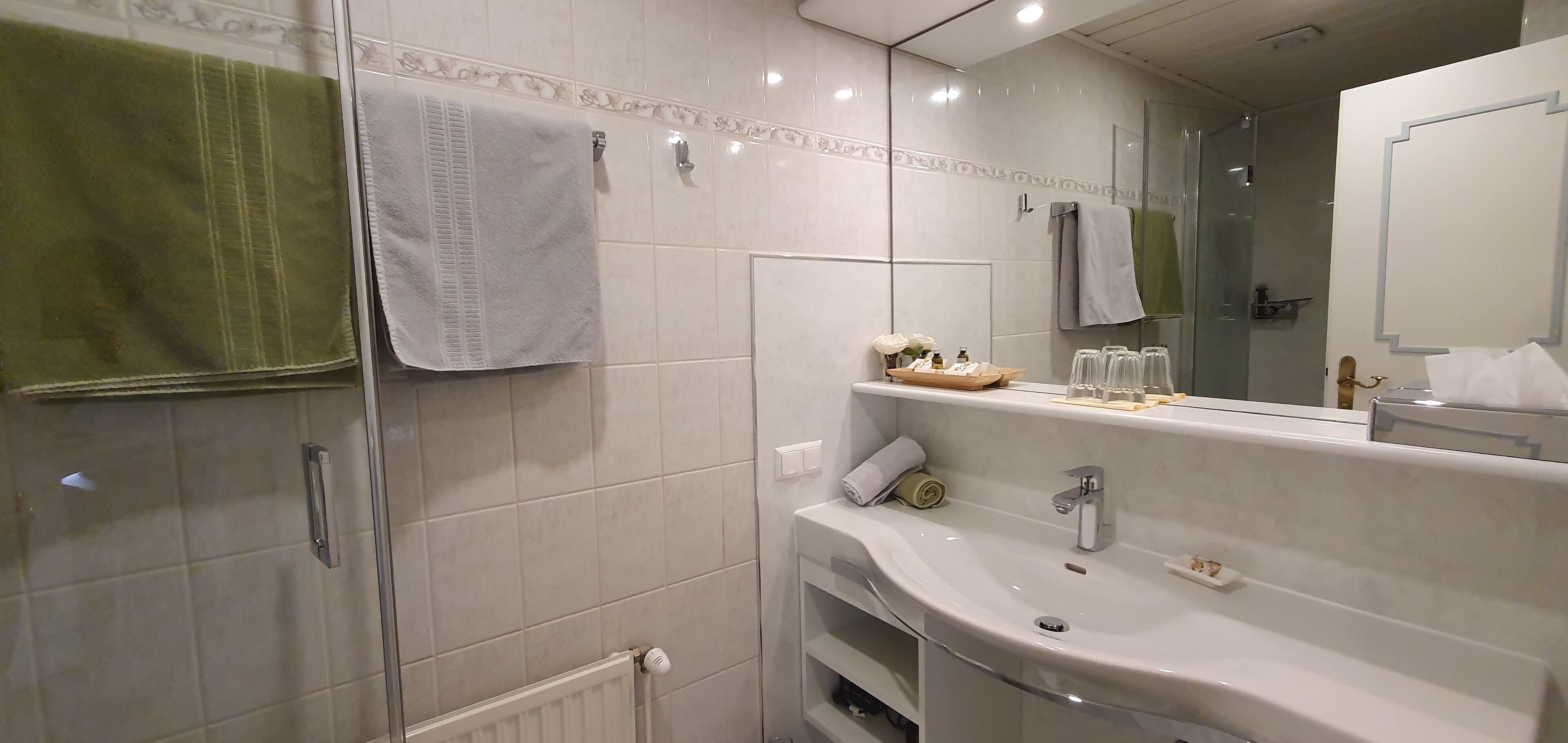 Un baño moderno con un espejo grande, un lavabo y una zona de ducha.