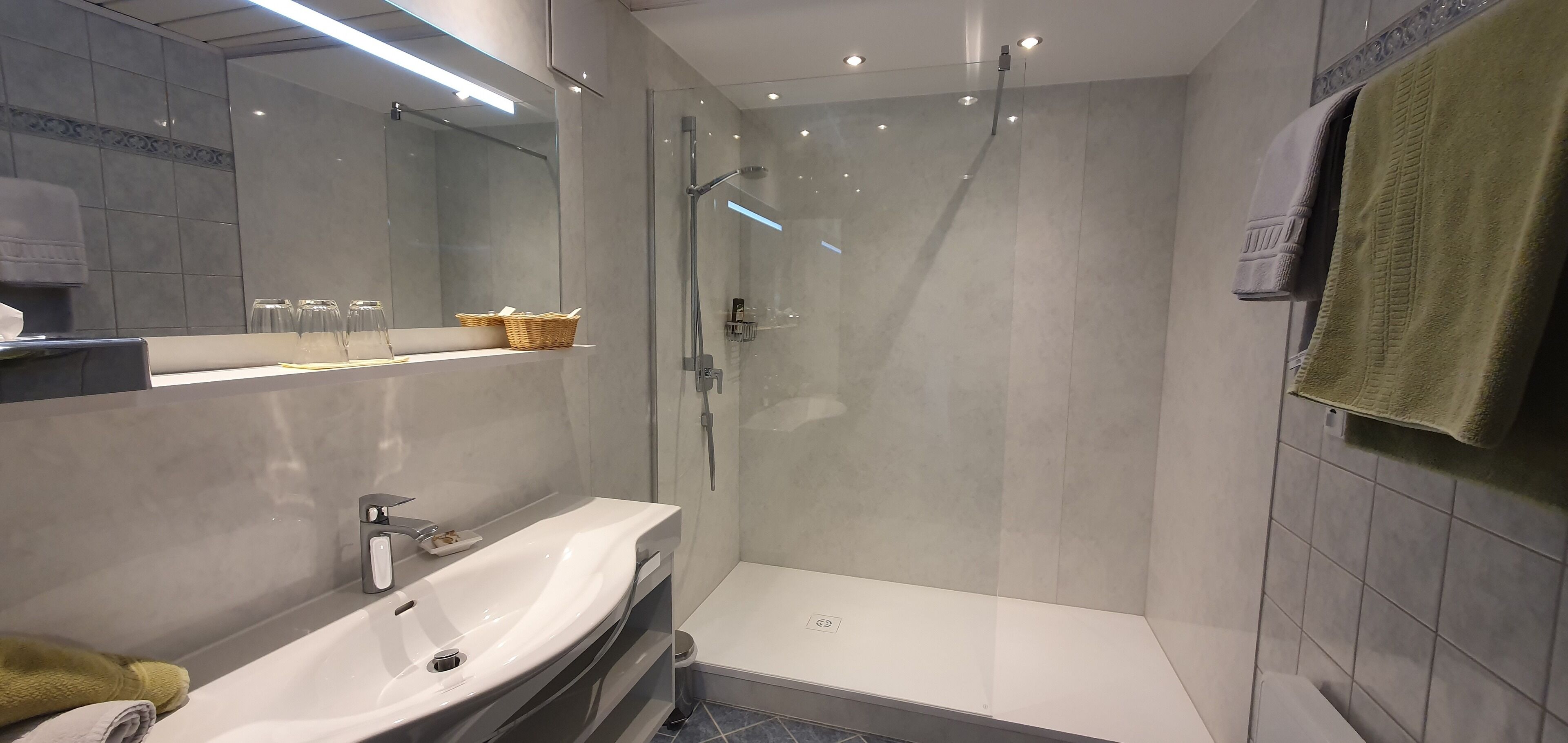 A modern bathroom with a glass-enclosed shower, a sink, and a mirror.