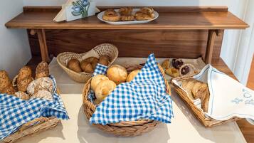 A buffet table with various breads and pastries in wicker baskets and cloths.