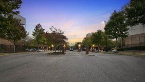 A parking lot with a gated entrance, surrounded by trees and buildings.