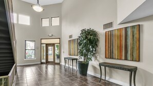A spacious hallway with a large potted plant, a bench, and artwork on the walls.