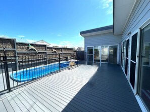 A wooden deck with a pool, a fenced area with decorative fish sculptures, and a sliding glass door leading to a covered patio. - Sorrento in Summer | Heated Plunge Pool & Spa | Pet Friendly (Sorrento)