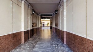 A corridor with a patterned floor, columns, and a ceiling with decorative moldings. - Umberto I Residence (Napoli)