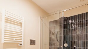 A bathroom with a bidet, a toilet, a glass-enclosed shower, and a patterned floor. - Umberto I Residence (Napoli)