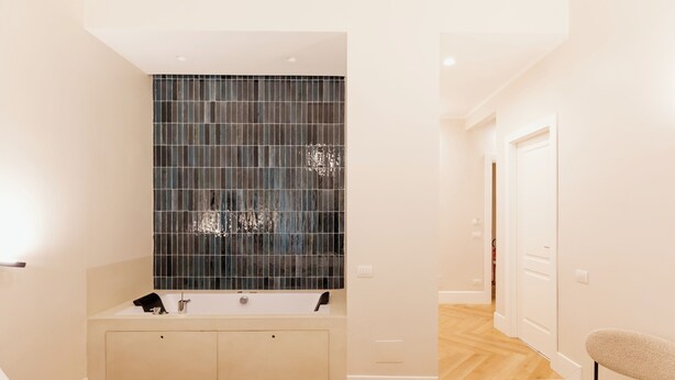 A modern bathroom with a large mirror, a bathtub, and a shower area. - Umberto I Residence (Napoli)