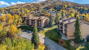 Zona residencial con edificios de varios pisos, un estacionamiento y un paisaje montañoso al fondo.