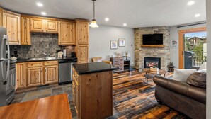 Una cocina moderna con armarios de madera, una chimenea de piedra y un sofá de cuero en una sala de estar.