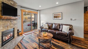 Una sala de estar con chimenea, sofá de cuero y una mesa de centro redonda.