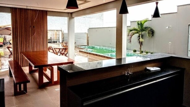 A modern kitchen with a central island, wooden dining table, and pendant lighting. - HOTEL ASA BRANCA (Seabra)