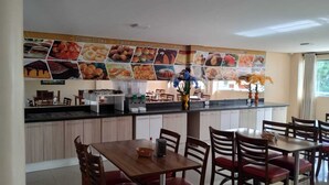 A modern kitchen with a central island, wooden cabinets, and a dining area with red chairs. - HOTEL ASA BRANCA (Seabra)