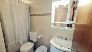 A bathroom with a toilet, sink, and mirror.