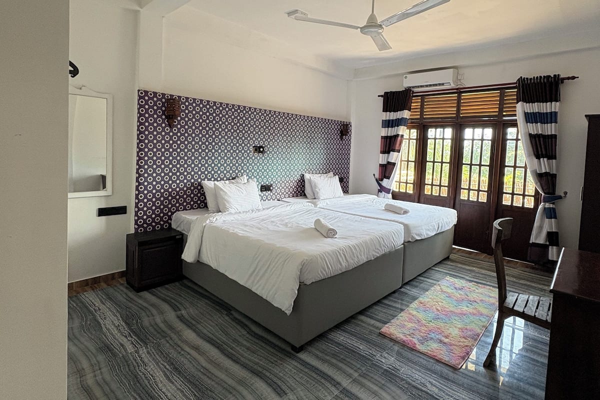 A spacious bedroom with a large bed, a ceiling fan, and a view through the window.