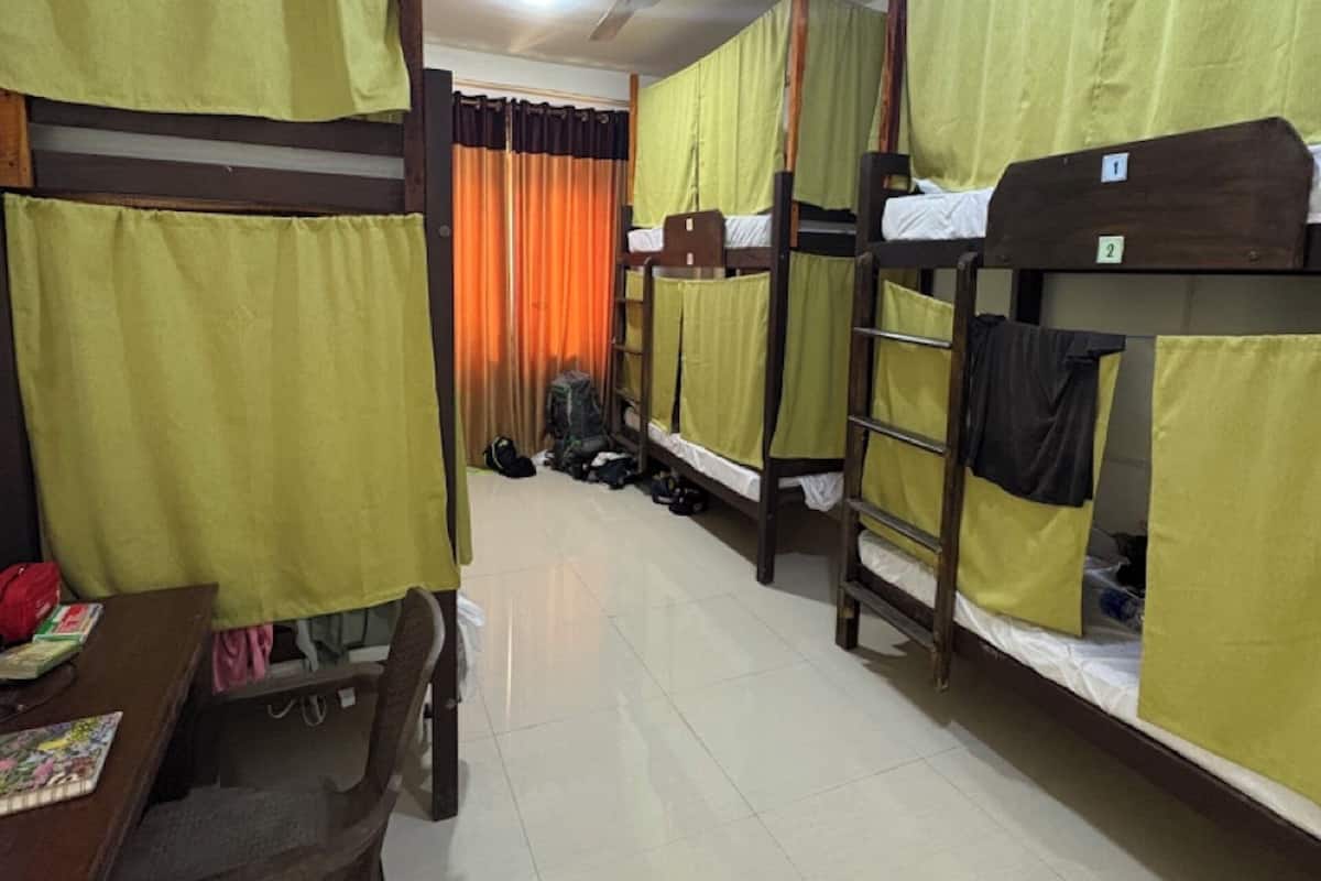 A dormitory room with bunk beds, a desk, and a chair.