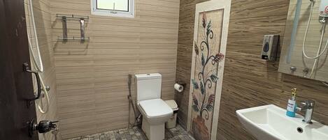 A bathroom with a toilet, shower, and sink.