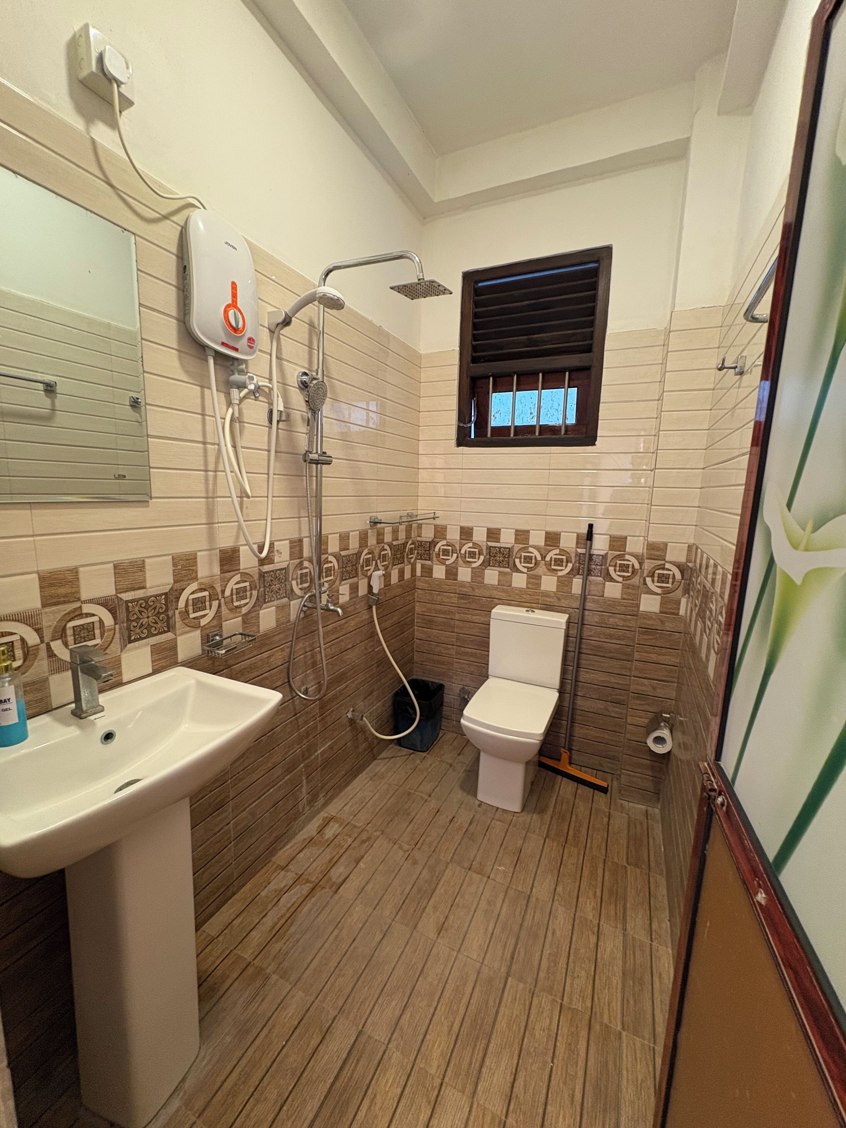 A bathroom with a sink, toilet, shower, and a window.