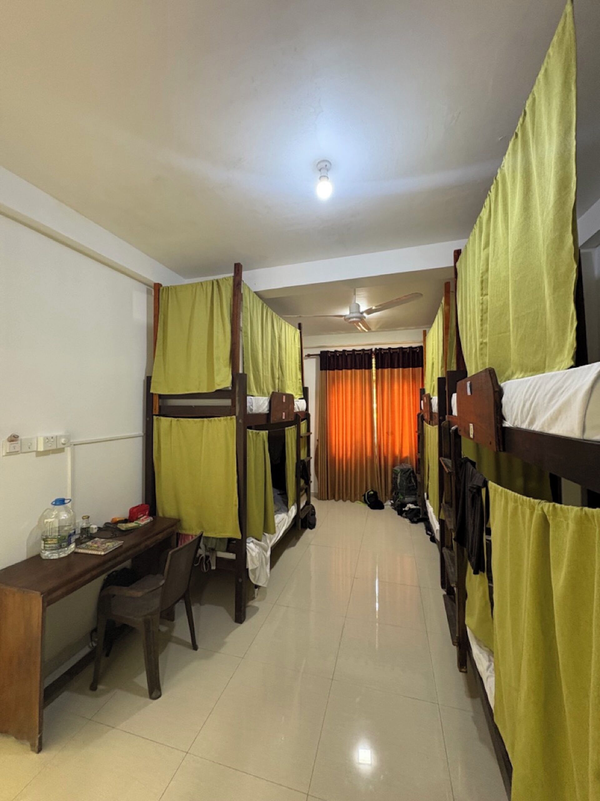 A dormitory room with bunk beds, a desk, and a chair.