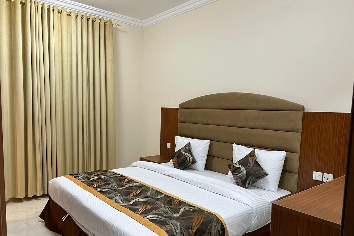 A hotel room with a large bed, a wooden headboard, and a nightstand.