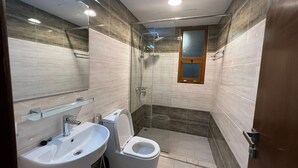 A modern bathroom with a glass-enclosed shower, a toilet, and a sink.