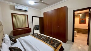 A bedroom with a bed, a wardrobe, an air conditioning unit, and a ceiling fan.