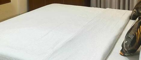 A hotel room with a bed, a wooden wardrobe, and a curtain.