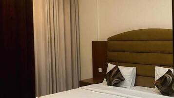 A hotel room with a bed, curtains, a ceiling fan, and a light fixture.