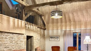 A spacious living area with a high wooden ceiling, stone walls, and a mix of traditional and modern furniture.