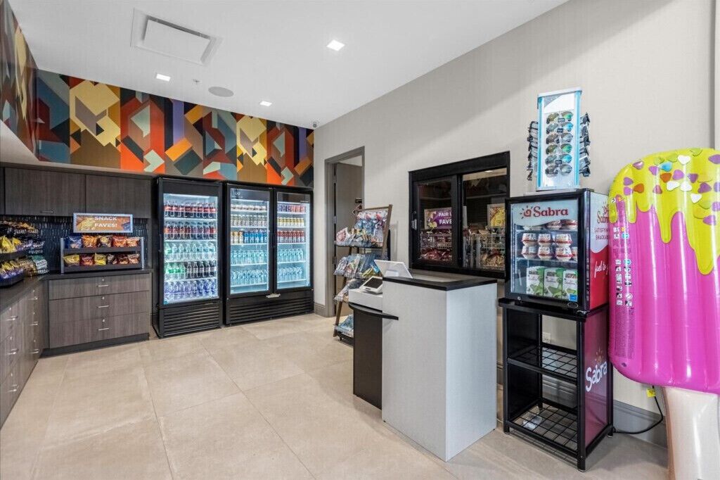 Un bar à collations moderne, doté d’un réfrigérateur pour les boissons, d’un distributeur automatique et d’un mur aux couleurs vives.
