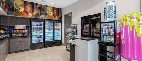 Un bar à collations moderne, doté d’un réfrigérateur pour les boissons, d’un distributeur automatique et d’un mur aux couleurs vives.