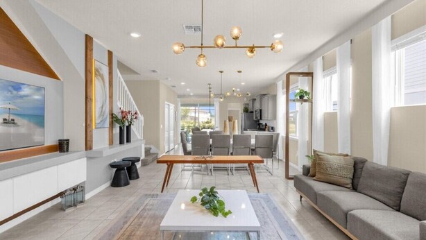 A spacious living area with a modern chandelier, a dining table, and a sofa.
