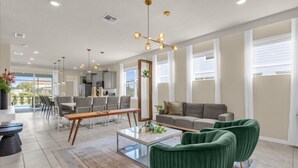 A spacious living area with a sofa, green armchairs, a coffee table, and a dining table.