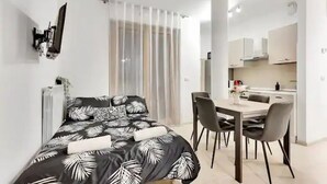 Een moderne slaapkamer met een bed, een eethoek en een kitchenette.
