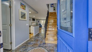 A hallway with a blue door, a staircase, and a kitchen area. - 28 Sol Vista Complex - Spacious, Deck, BBQ, Common Pool + GOLF CART (Avalon)
