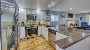 A modern kitchen with stainless steel appliances, white cabinetry, and a granite countertop. - 28 Sol Vista Complex - Spacious, Deck, BBQ, Common Pool + GOLF CART (Avalon)