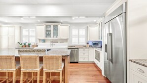 Una cocina moderna con armarios blancos, un refrigerador de acero inoxidable y una encimera de granito.