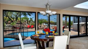 Comedor con vista a una piscina y mobiliario para exteriores.