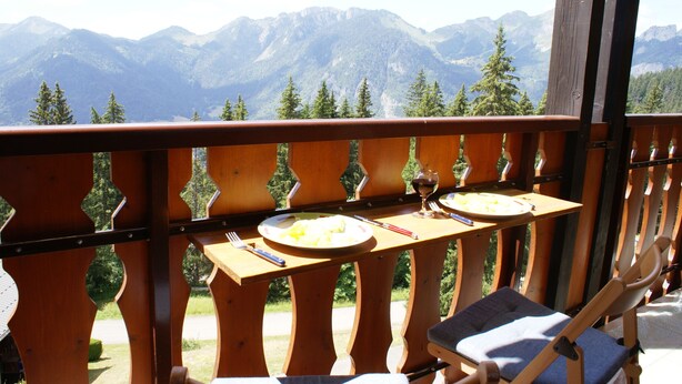 A wooden balcony with a table set for two, overlooking a mountainous landscape. - Magnificent panorama (Le Biot)