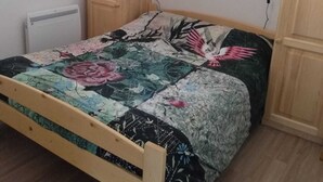 A bedroom with a bed, wooden cabinets, a radiator, and a window. - Magnificent panorama (Le Biot)